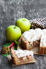 Tasty meringue pie with rhubarb and apple on wooden table
