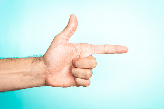 Thumb up and index finger making gun on blue background. Social media as weapon, Guerrilla marketing concept.