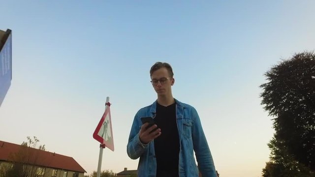 Young guy looking into mobile browsing facebook Walking outdoors Having time on his own