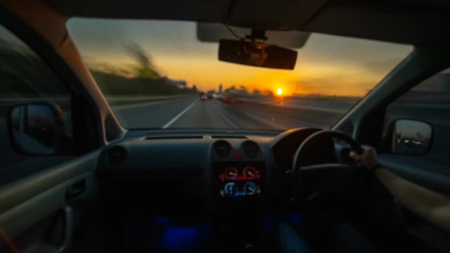 The man driving a car on the sunrise background. Hyperlapse