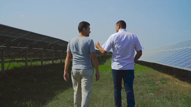Two businessmen walk in rows of solar cells