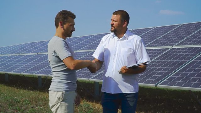 Two business people shaking hands on the background of solar cells