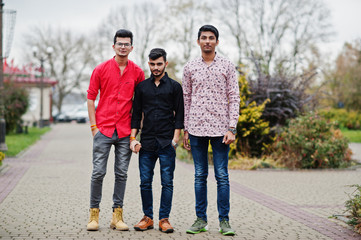 Three indian guys students friends walking on street.