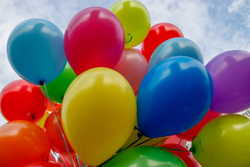 A large bunch of colored balloons on a blue sky background.