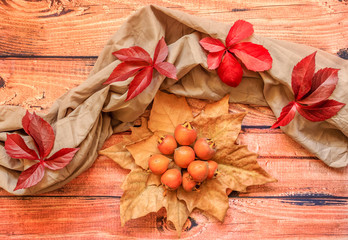 A pile of ripe medlar on a golden leaves and red leaves around them on wooden background