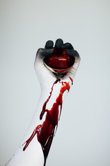 Creepy Halloween bloody woman monster hand and arm with white and black make up holding vintage cup...