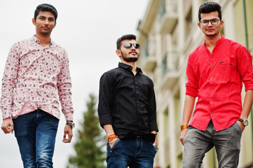 Three indian guys students friends walking on street.