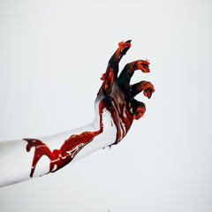 Creepy bloody horror Halloween monster witch hand with white, red and black make up and long creepy...