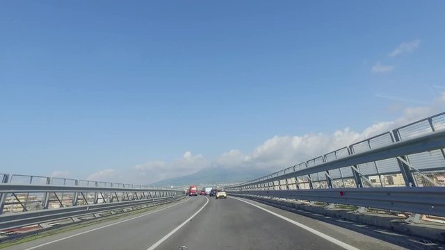 Driving on a narrow and busy highway with extended guard rails high above the city in Europe
