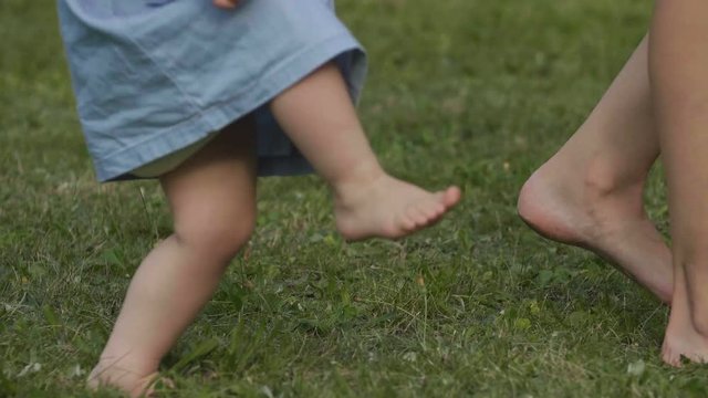 Close-up baby barefoot walks on summer green grass. Baby have fun.  Happy family concept.