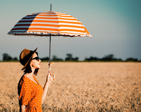 photo of the beautiful young woman with red umbrella standing in the field