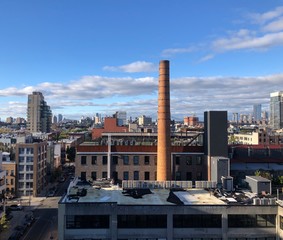 Industrial chimney smokestack and rooftops in skyline of popular Williamsburg, Brooklyn waterfront in New York City