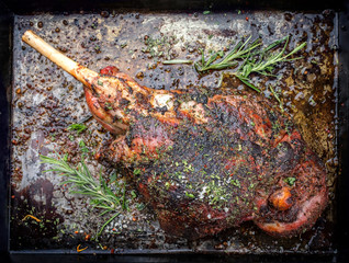 Traditional barbecue leg of lamb with spice and herb as top view on a metal sheet