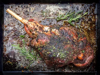 Poster Traditional barbecue leg of lamb with spice and herb as top view on a metal sheet © HLPhoto