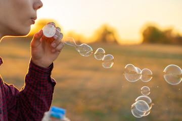 person blow soap bubbles on a sunset in nature field f