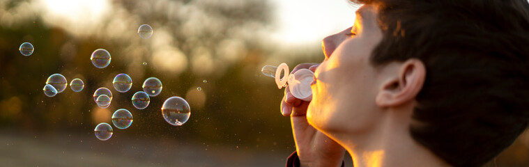 person blow soap bubbles on a sunset in nature field f