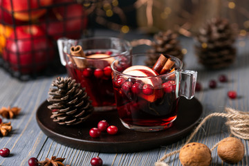 Mulled wine in glasses on a wooden background. Apples, cranberries, cinnamon, star anise, walnuts,...