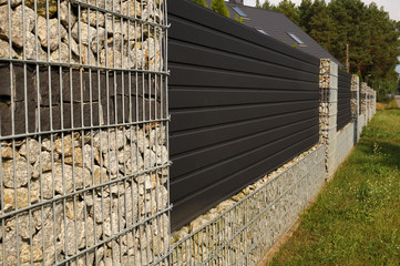 A modern wall. A fragment of a long fence of a house made with the help of gabions.