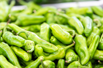 Macro closeup of many green hot peppers in farmer's market or Italian street food stall in Rome, Italy