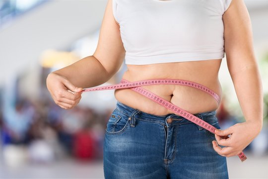 Overweight, fat woman measuring her stomach on