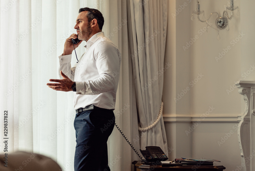 Wall mural Man on business trip talking on hotel room phone