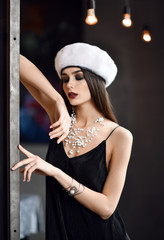 woman in white winter fir hat cap  in expensive loft restaurant touching wall with finger 