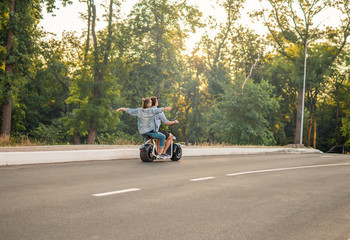 Lovely young couple driving electric bike during summer Modern city life and transportation