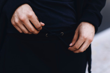 Fototapeta premium Man tying the lace on sports trousers. Man wearing black sport suit. Clothing details. 