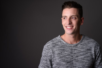 Obraz premium Face of young happy man thinking against gray background