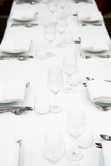 Beautifully decorated table with empty white plates, glasses and cutlery  on luxurious tablecloths