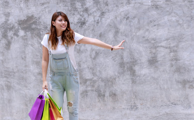 Attractive joyful excited young woman holding colorful shopping bags on concrete walls background with copy space. happiness, consumer, sale and people concept.