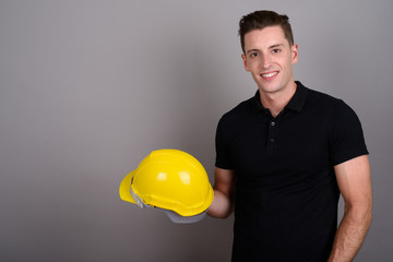Young handsome man construction worker holding hardhat