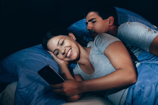 Jealous husband watching his wife mobile phone on the bed at home