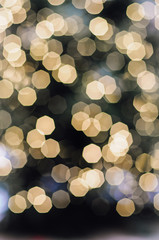 Blurry, golden, illuminated Christmas fairy lights on outdoor xmas tree at the Nuremberg Christkindles market in winter creating a beautiful out of focus bokeh effekt.