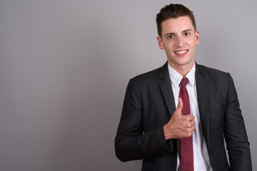 Young handsome businessman smiling and giving thumb up