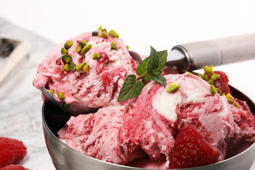Raspberry ice cream scoop with chopped nuts and white chocolate on a rustic background