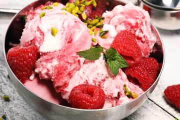 Raspberry ice cream scoop with chopped nuts and white chocolate on a rustic background