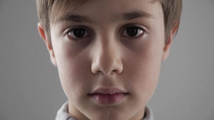 Close up Portrait of cute young 11 - 12 year old boy looking at the camera on white background