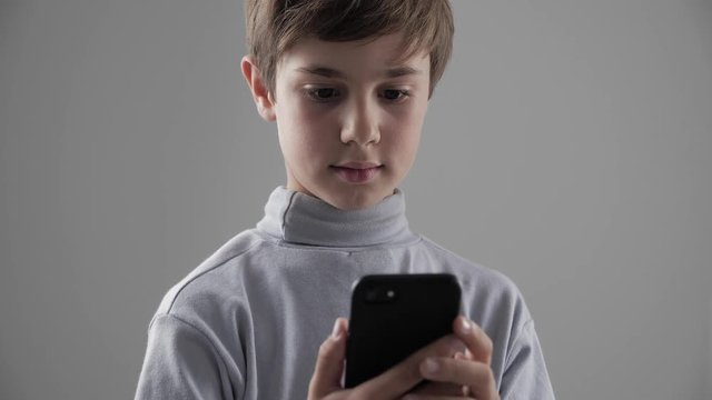 Portrait of Young Child Boy using Smartphone on white background. Boy plaing games on smartphone.