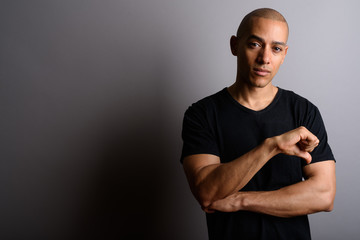 Obraz premium Handsome bald man giving thumb down against gray background