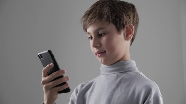 Portrait of Young Child Boy using Smartphone on white background. Boy plaing games on smartphone.