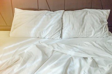 Two white pillows with white bedding sheet on empty bed in bedroom for rest and relax