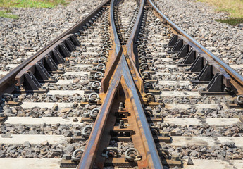Close up two rusty old steel railway track switch,point two paths come together