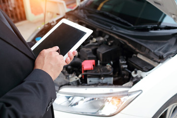 Insurance agent using tablet for insurance claim with broken car