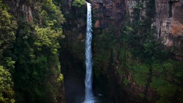 Aerial drone shot of a steep, long waterfall in the jungle of Drakensberg, South Africa.