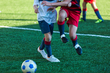 football teams - boys in red, blue, white sportswear play soccer on the green field. boys dribbling. dribbling skills. Team game, training, active lifestyle, hobby, sport for kids concept