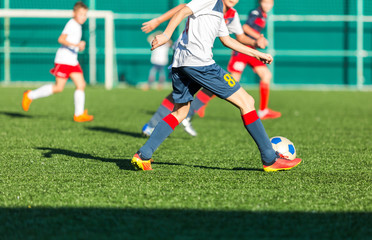 football teams - boys in red, blue, white sportswear play soccer on the green field. boys dribbling. dribbling skills. Team game, training, active lifestyle, hobby, sport for kids concept