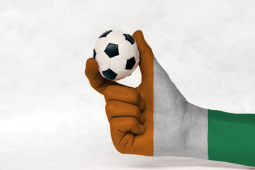 Mini ball of football in Ivory Coast flag painted hand on white background. Concept of sport or the...