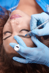microblading close-up, hands adding pigment to eyebrows.