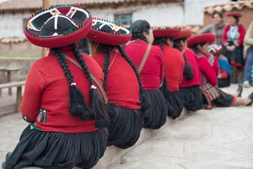 Foto op Canvas Quechua women sitting in a line with their traditional dress and braided hairstyle in Peru. © ludovica